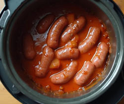 Image montrant des saucisses de porc braisées dans une sauce tomate dans une cocotte